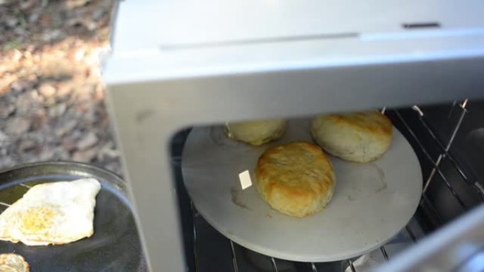 在野营烤箱中烹饪饼干，用铸铁煎锅煎鸡蛋