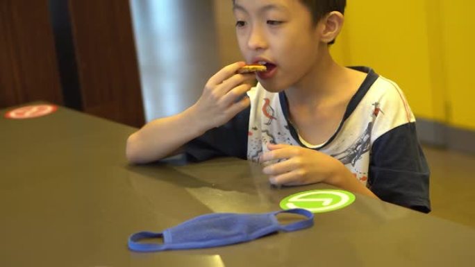 中国孩子把口罩放在桌子上吃汉堡