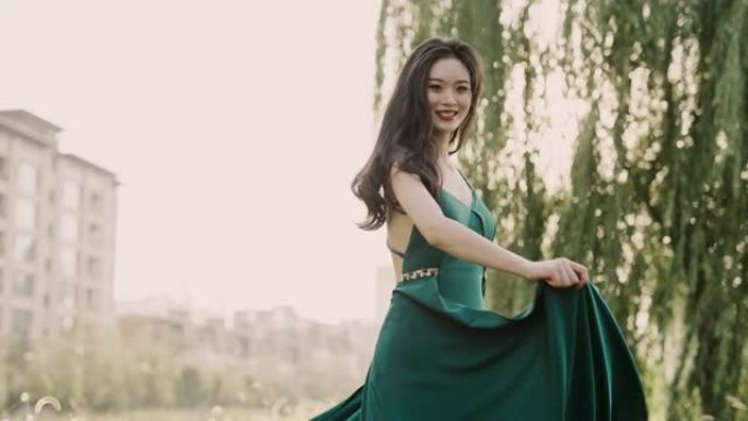 年轻美丽的亚洲女性穿着绿色的裙子，在夕阳中奔跑，穿着晚礼服的中国新娘