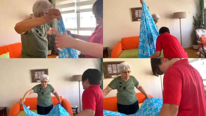 11岁的男孩帮助他的祖母折叠床单。
