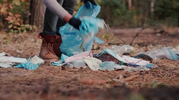 一名妇女从森林中的医用口罩和塑料中清除垃圾