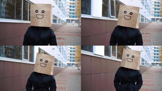 微笑快乐的纸袋脸走在街上。有趣的女人穿着面容愉快的面包袋