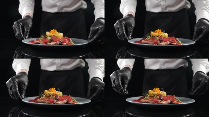 餐厅美食概念。厨师在厨房展示他的餐盘。特写。餐厅食物烹饪和上菜。厨师手拿盘子放在桌子上。高清