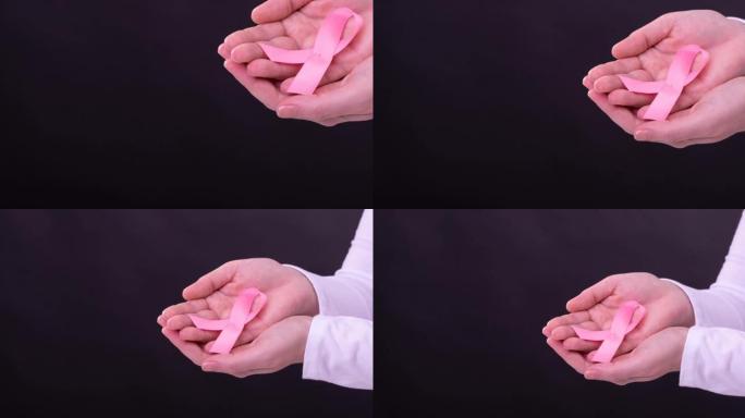 白人妇女手持粉红癌症意识丝带，黑色背景的中段视频
