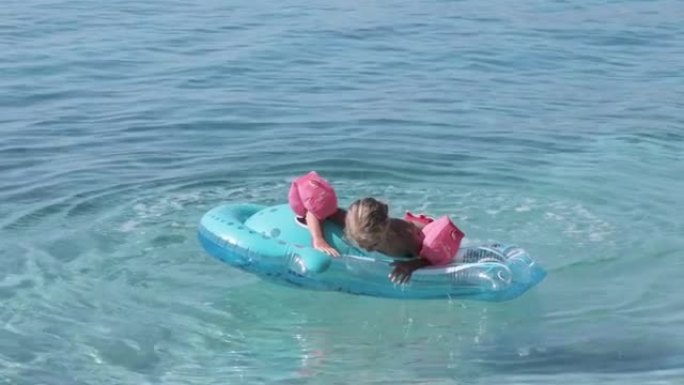 孩子在海里用充气床垫游泳。