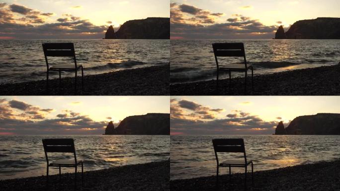日落时海滩上戏剧性的海景，前景是空椅子，温暖的日落照亮了岩石火山悬崖。没人。平静沉默与自然统一的概念