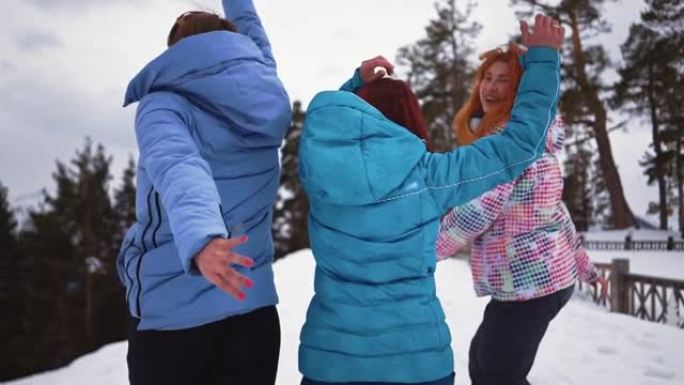 三个快乐的女孩在雪地里奔跑。快乐的女人在冬天的森林里玩搞笑