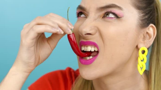 年轻的女人尝红辣椒。