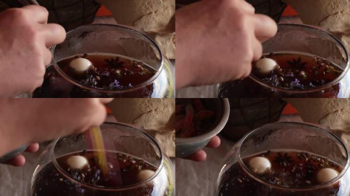 手将果冻糖果的眼睛和果冻蠕虫放入神奇药水的玻璃碗中