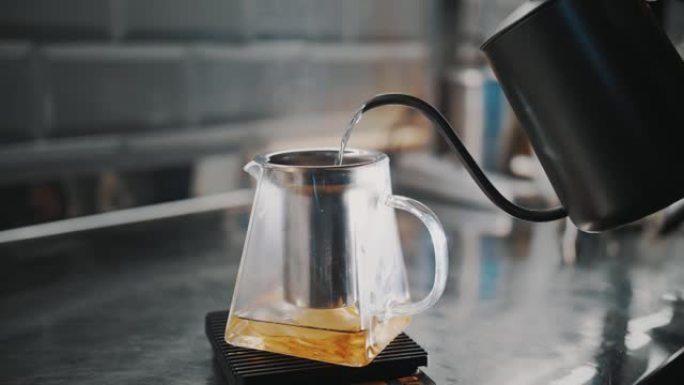 茶饮料。泡茶。特写。茶师用梨片将沸水倒入玻璃茶壶中。特制热果茶饮料的烹调工艺