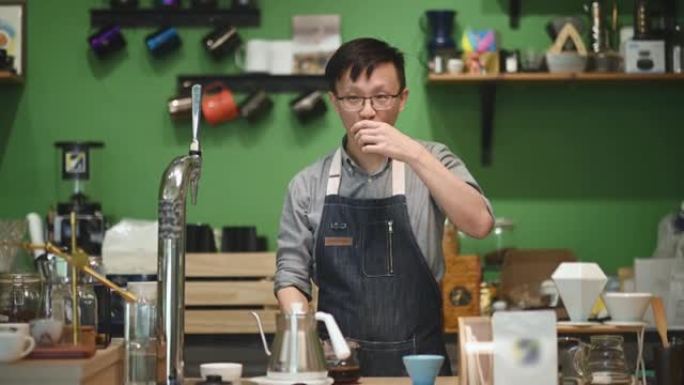 亚洲中国咖啡师咖啡馆老板在咖啡馆酒吧柜台享用研磨咖啡