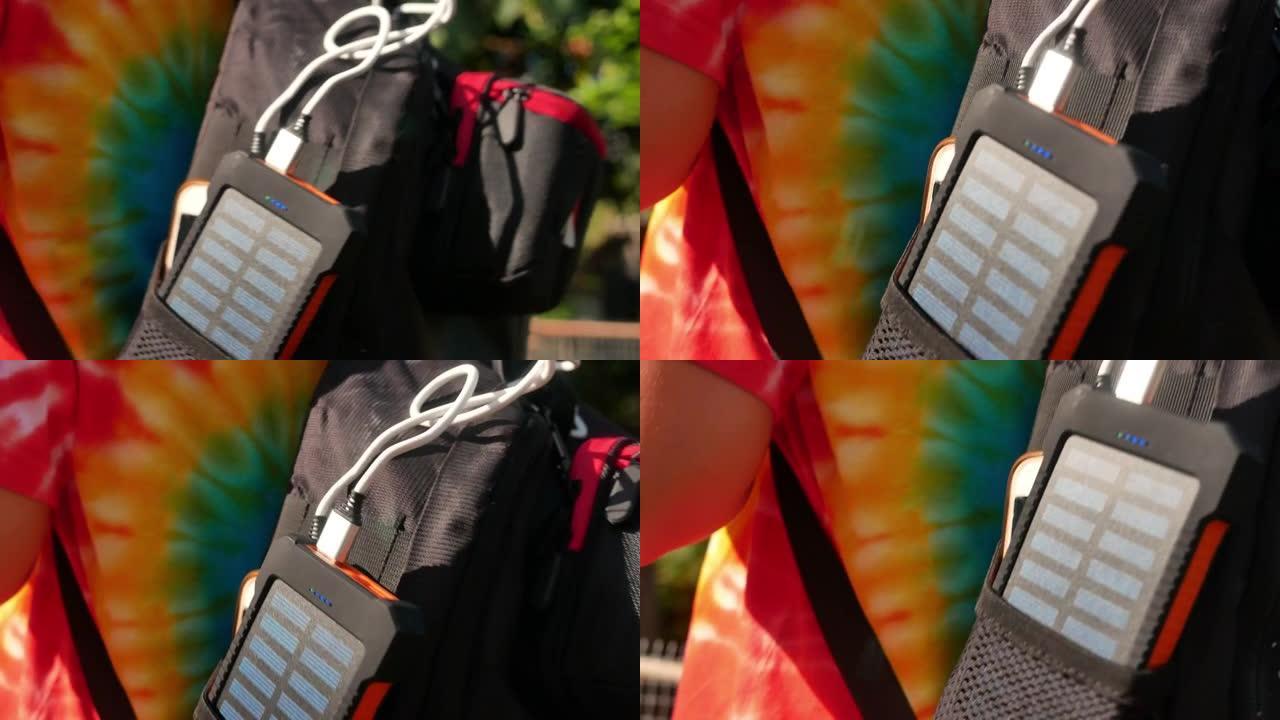 年轻女性旅行者背包中带有太阳能电池板的可充电移动电源组，特写镜头。连接到手机、平板电脑或智能手机并为