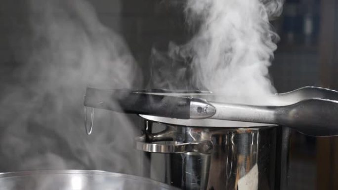 蒸汽或蒸汽云来自炉子上平底锅中的沸水。烹饪时从锅里蒸云。慢动作烹饪过程。蒸汽和白烟在黑暗的背景下升起