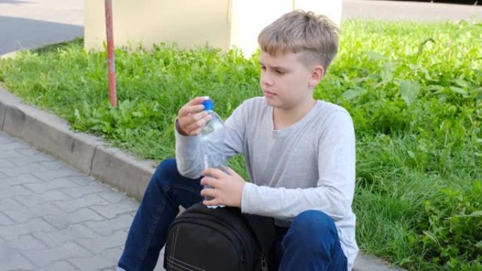 小学生从学校背包里拿出瓶子喝水。