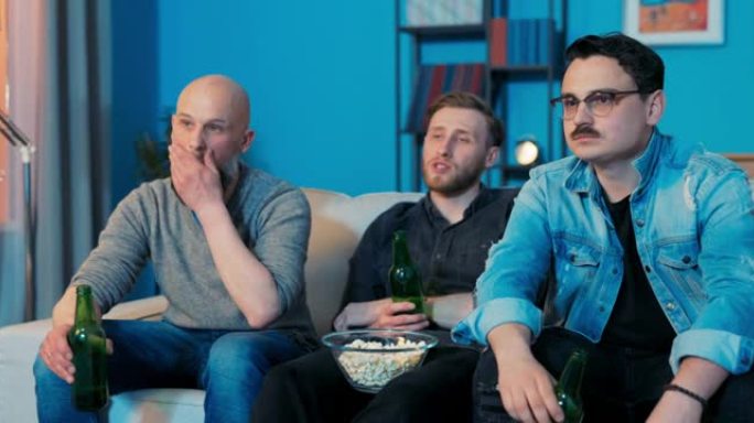 晚上，三个伙伴坐在客厅的沙发上，看他们最喜欢的电视连续剧电影，喝啤酒，吃碗里的零食，一起评论电视上的