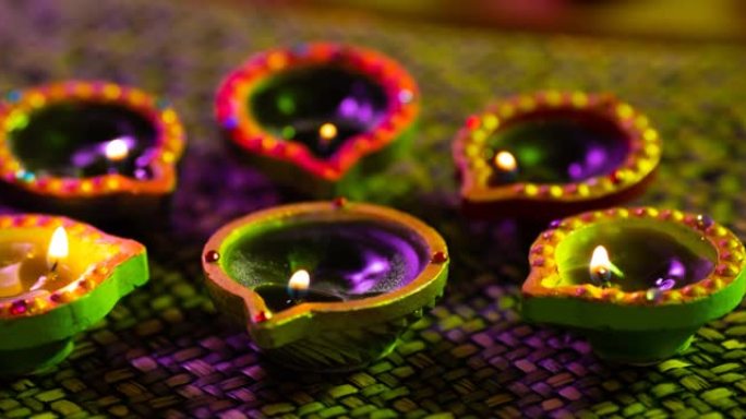 在紫色到绿色的编织表面上圆形发光的排灯节蜡烛的视频