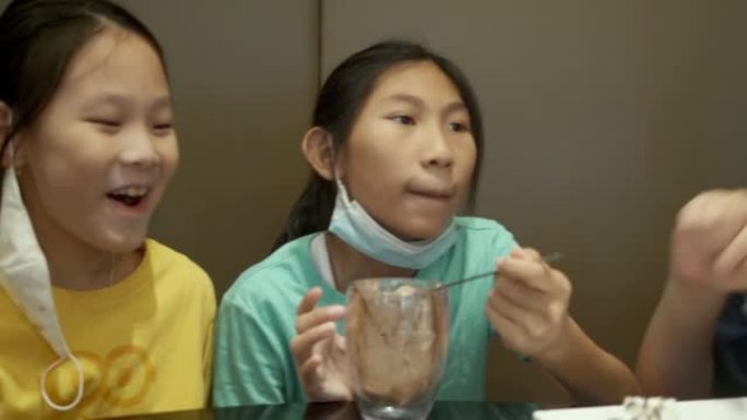 四个亚洲孩子在餐厅一起吃冰淇淋蛋糕作为生日部分，生活方式概念。