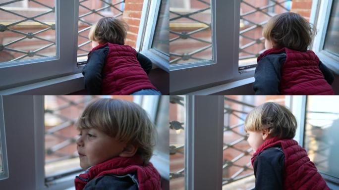 孩子透过窗户向外看。小男孩靠在阳台上凝视着外面