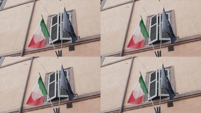 意大利和欧盟的旗帜悬挂在石板外墙的意大利古建筑的百叶窗下，两面旗帜象征着国家之间的合作和伙伴关系。国