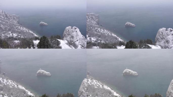 白雪覆盖了海上的岩石悬崖。海湾上的冬季景观。雪下的杜松树。寒假、旅行和娱乐的概念。克里米亚塞瓦斯托波
