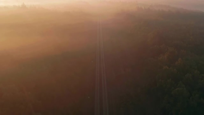 货运列车在日出时穿过雾蒙蒙的森林。鸟瞰图。
