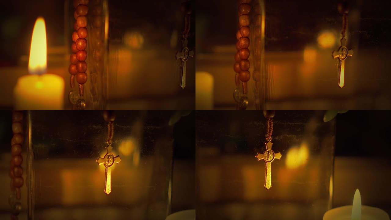 在黑暗中平移蜡烛旁的圣本尼迪克特念珠的选择性焦点镜头