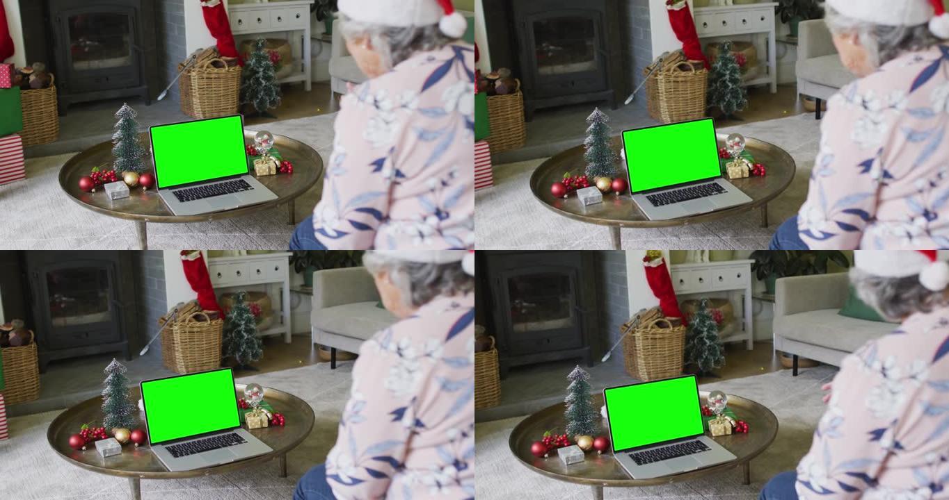 戴着圣诞老人帽子的白人高级妇女用绿色屏幕拨打笔记本电脑圣诞节视频通话