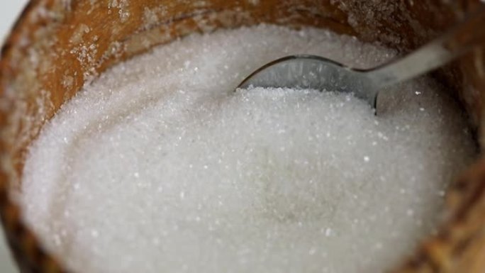 用勺子从糖碗中拿起白糖的过程特写，慢动作。不健康饮食观念，糖瘾，糖尿病