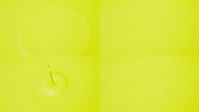 一滴丙烯酸涂料进入涂料中。黄色彩色斑点背景。浅绿色彩色黄色抽象。