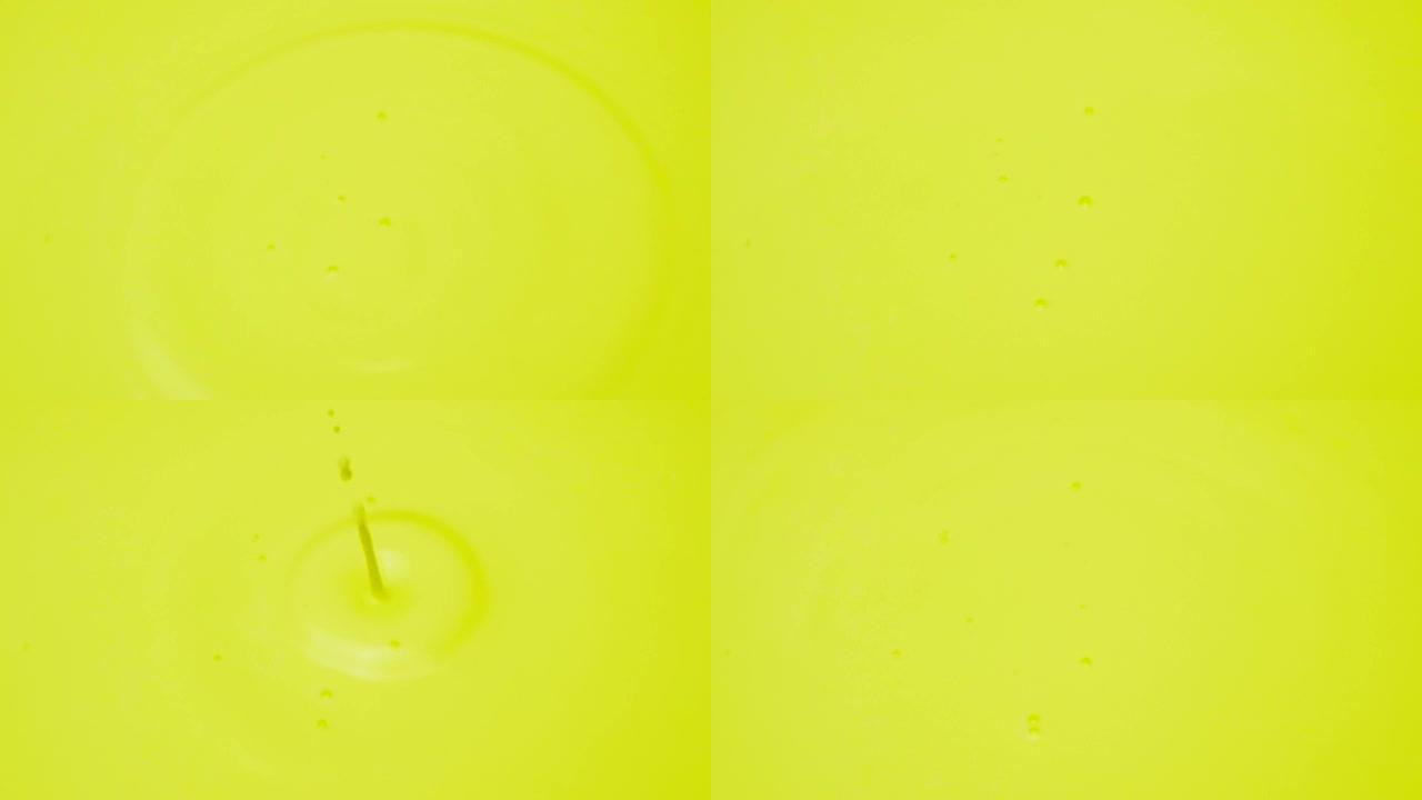 一滴丙烯酸涂料进入涂料中。黄色彩色斑点背景。浅绿色彩色黄色抽象。