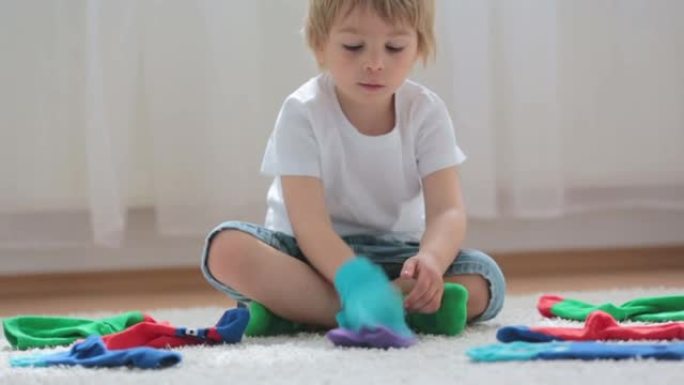 孩子学习如何成对放置不同的袜子，孩子坐在地板上玩袜子