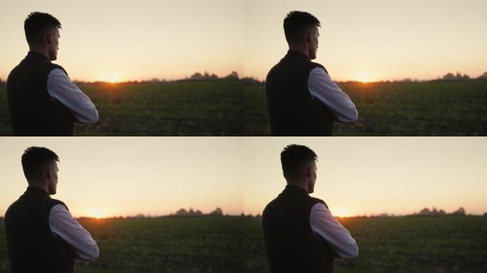 一个农民看着远处的田野，在日落时独自站立