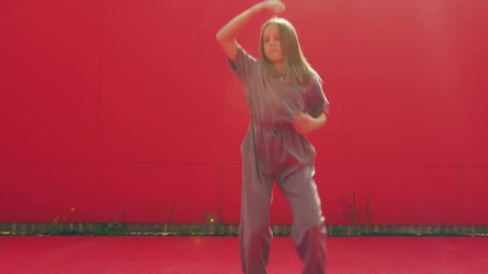 酷女孩少年在户外红墙背景上跳舞当代充满活力的表现力舞蹈。舞蹈动作，节奏