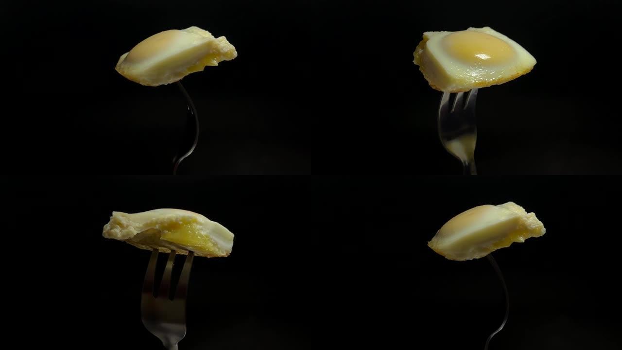 叉子上的一块炒鸡蛋在黑暗的背景下旋转