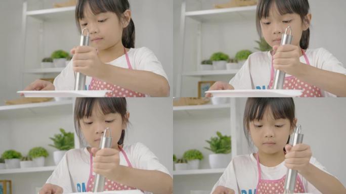 快乐的亚洲孩子在家里学习做饼干，女孩在搅拌碗里搅拌面粉。