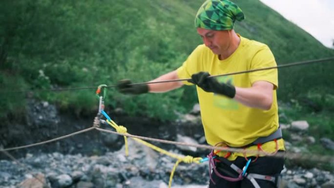 一名游客使用垂直绳索过河，并用登山扣固定