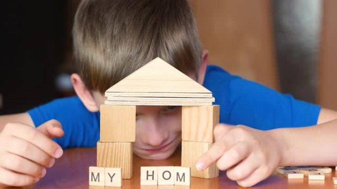 孩子玩积木盖房子。这个男孩梦想着一个新家。我家的字体是用一个孩子手中的立方体制成的。选择性聚焦，浅景