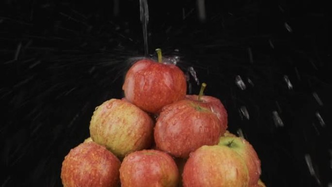 慢动作。水流落在旋转的成熟苹果堆上。隔离