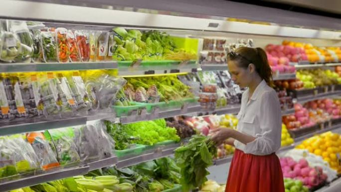 超市杂货店里的新鲜蔬菜。女人在冰箱里选择生菜