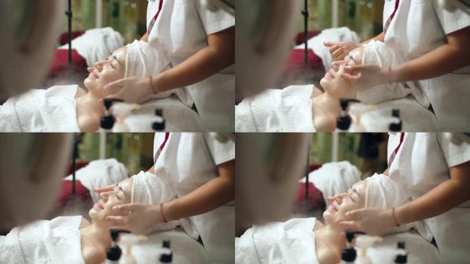 美丽的女性在皮肤护理水疗中心获得面部皮肤蒸腾保湿治疗