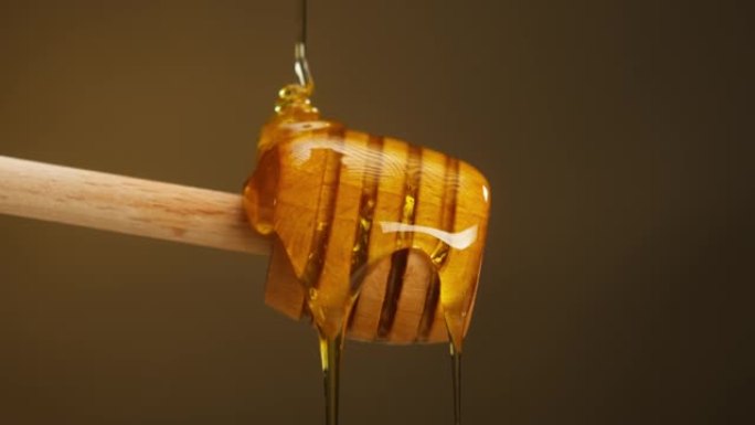 木勺上流动的甜蜜蜜-纺锤特写。收集新鲜的蜜蜂蜂蜜。健康生态的天然糖食品。养蜂和收获