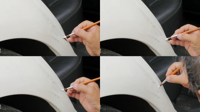 手工特写-一名男子在汽车油漆店用白色油漆覆盖后门线上的划痕。