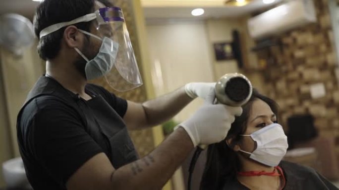 一名水疗中心男性工作人员戴着口罩，给女客户理发