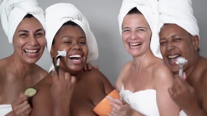 多种族女性戴着毛巾享受水疗日与美容面膜 -- 不同肤色和身体的多代朋友