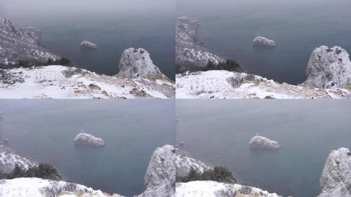 白雪覆盖了海上的岩石悬崖。海湾上的冬季景观。雪下的杜松树。寒假、旅行和娱乐的概念。克里米亚塞瓦斯托波