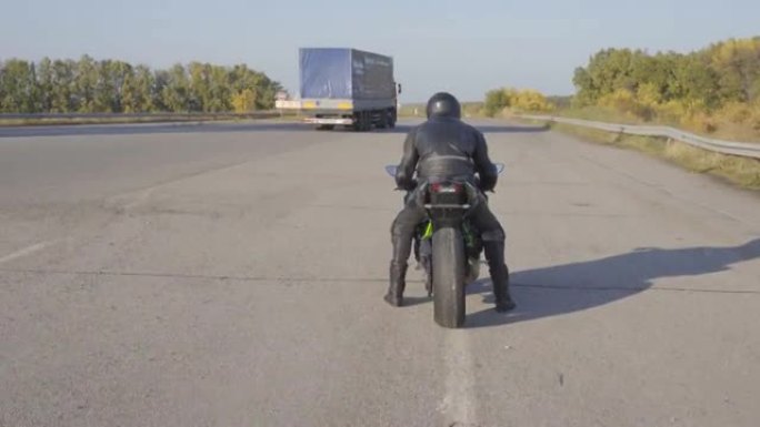 坐在乡间道的运动摩托车上准备骑行时，摄像机会移到年轻的摩托车手身上。穿着摩托车防护装备的男性摩托车手