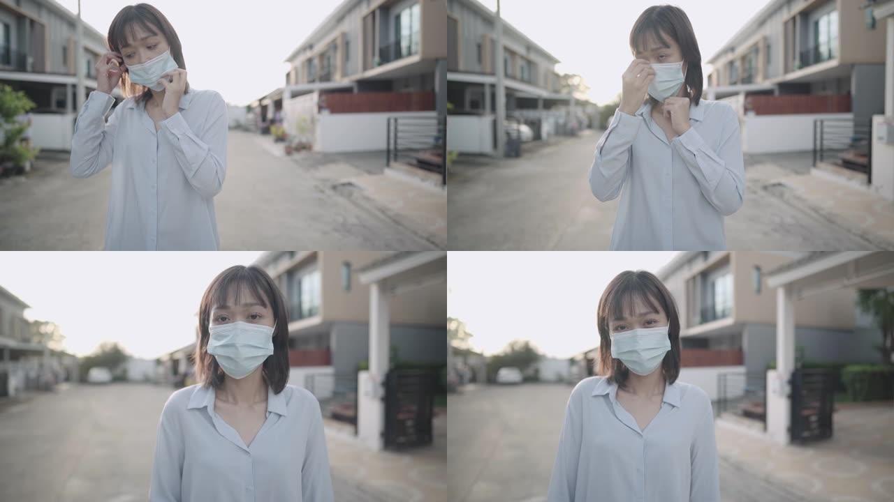 一名忧心忡忡的棕色短发妇女在村街的家外戴上医用口罩，保护呼吸免受感染冠状病毒、大流行、防疫、外出