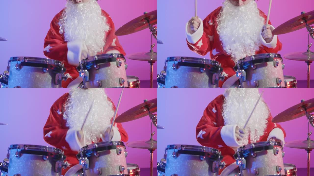 一个打扮成圣诞老人的男人在黑暗的工作室里在明亮的紫色灯光背景下演奏鼓包。穿着狂欢节服装的音乐家在圣诞