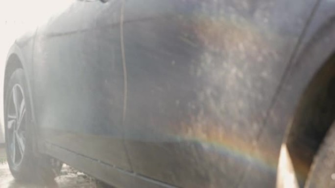 自助洗车。车主在洗车场亲自洗车。洗车时，水流产生了彩虹。选择性聚焦