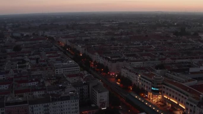 平移和倾斜早晨城市的镜头。日出前，宽阔的街道两旁是多层唐楼，橙色的暮色天空。德国柏林